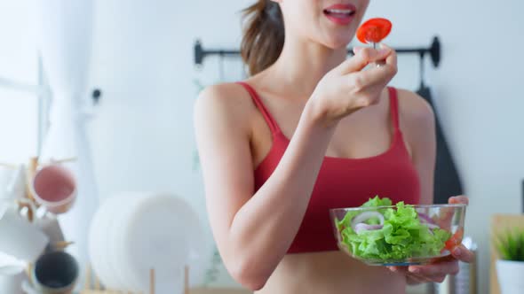 Close up of Asian attractive woman hold salad bowl and enjoy eat clean vegetables after exercise.