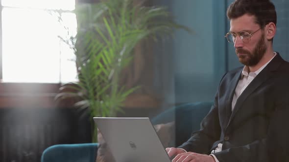 Portrait of an Elegant Businessman Sitting with Laptop on the Couch at the Luxury Blue Office