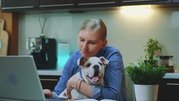 Close-up Shot of Cheerful Woman Hugging Small Dog in the Kitchen