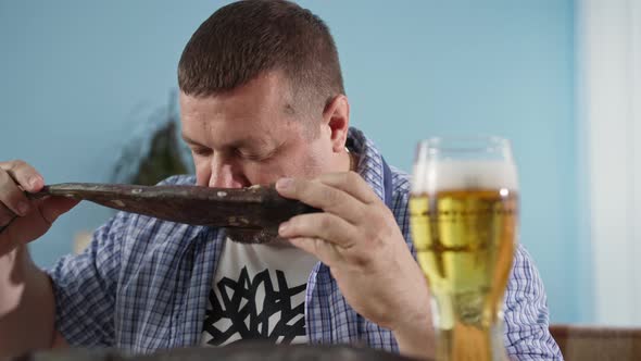 Young Man with Fish in His Hands Enjoys the Aroma of Delicious Fresh Seafood and Beer in a Glass