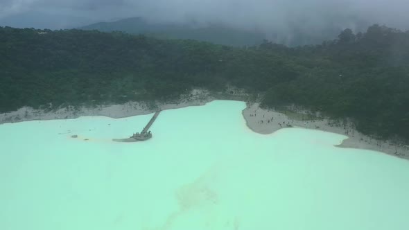 wide aerial landscape of volcano crater rim with neon sulfur lake at Kawah Putih in Bandung Indonesi