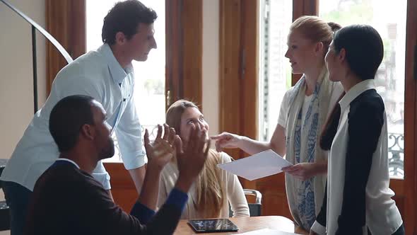 Woman delivering good news to her colleagues in casual meeting