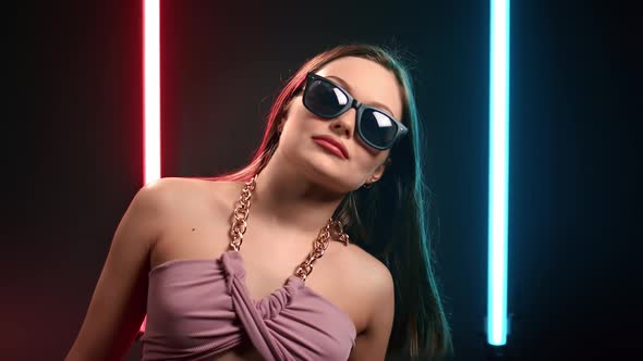 Fashion Woman in Sunglasses Dancing Raising Hands at Illuminated Glow Flashing Dance Floor Nightclub