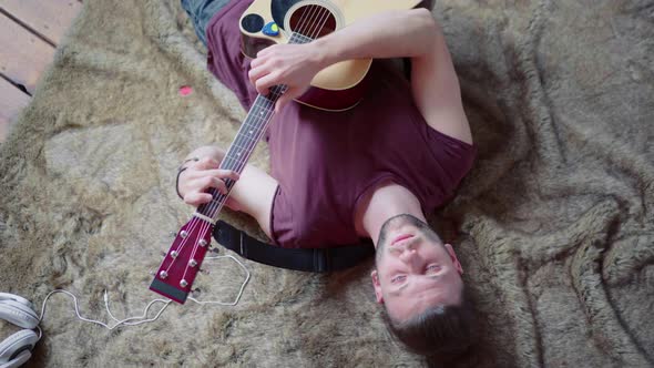 Man with Acoustic Guitar Singing and Playing Guitar in Lying Position