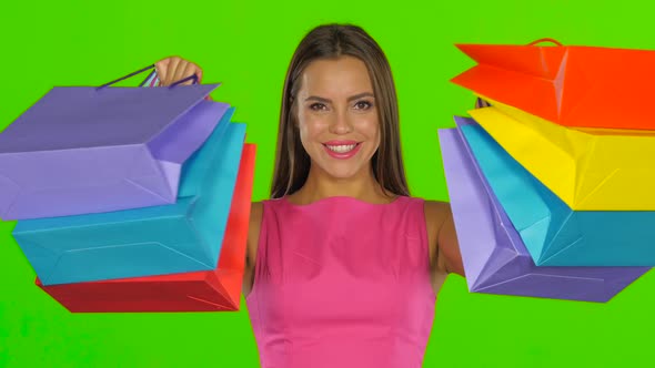 Woman Joyfully Looks Out From Behind Shopping Bags. Green Screen. Close Up