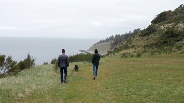 Couple walking towards the beach with their dog.