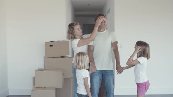 Two Cheerful Girls and Their Mom Leading Dad with Closed Eyes