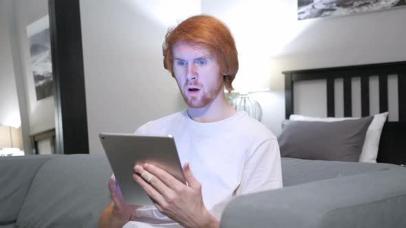 Reaction to Loss By Redhead Man Using Tablet in Bedroom