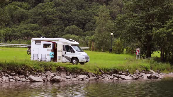 Woman is Standing with a Mug of Coffee near the Camper RV