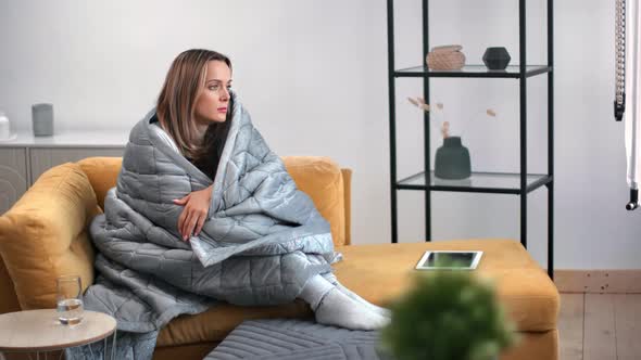 Melancholic Lonely Female Pensive on Couch Wrapped By Warm Blanket