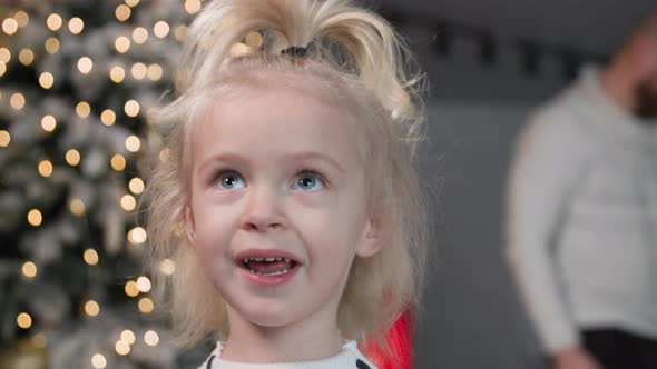 Portrait of Charming Sweet Girl Smiling and Looking Around Background of the New Year Tree in Room