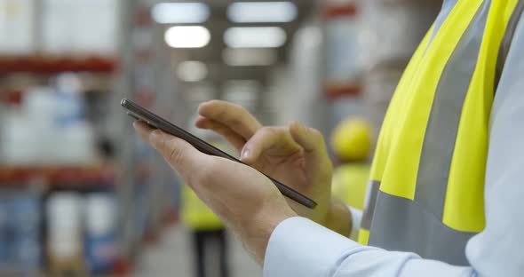 Close Up of Warehouse Worker Using Mobile Phone at Workplace