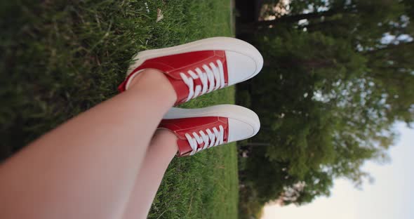 Female Legs in Red Gumshoes Resting on a Grass Vertical Video