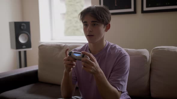 Beautiful Excited Young Gamer Man Sitting on a Couch Playing and Winning in Video Games on a Console