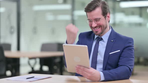 Excited Young Businessman Celebrating Success on Tablet