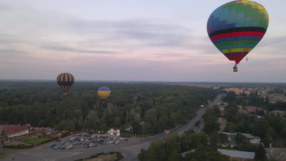 Colorful Hot Air Balloons Flying Over Green Park in Small European City at Summer Sunrise, Aerial