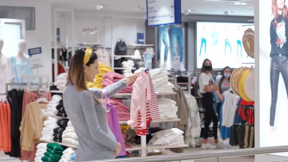 Pregnant Woman Buying Children's Clothing at Shop