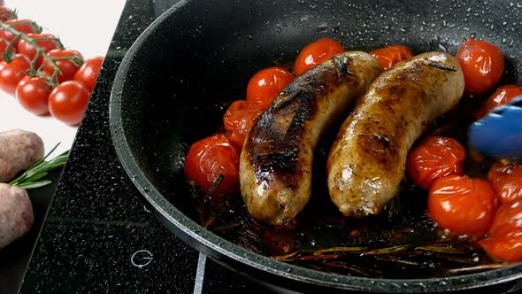 Fatty White Bavarian Sausages with Tomato and Sprig of Rosemary are Fried in Frying Pan