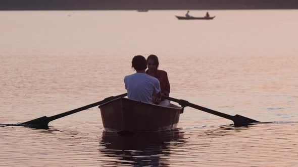 A Couple Sailing on the Boat Using Paddles - Beautiful Sunset
