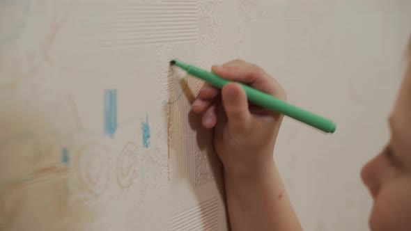 Closeup As a Caucasian Boy Draws with a Marker Felttip Pen Tree on Wallpaper
