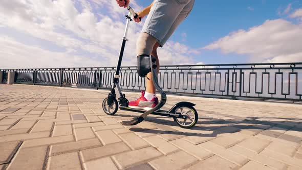 A Man with a Leg Substitute Is Riding a Scooter