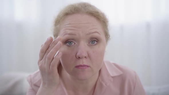 Close-up of Worried Caucasian Senior Woman Using Camera As Mirror. Portrait of Redhead Chubby Lady