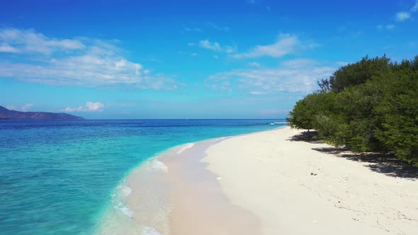 Natural overhead travel shot of a white sand paradise beach and blue ocean background in 4K