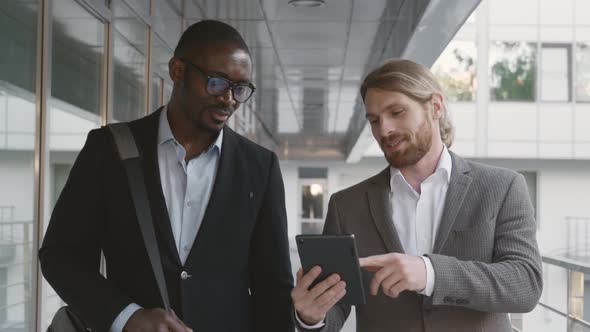 Diverse Businesspeople Commuting on Street and Discussing Project on Digital Tablet