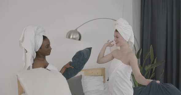 Multiracial Models Fighting with Pillows on Bed