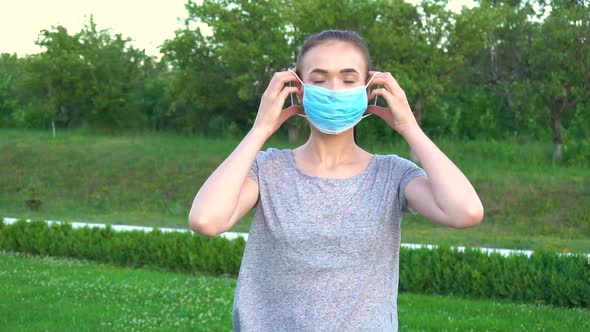 Woman Wearing Protective Mask Outdoor in the Park and Show Peace Gesture.