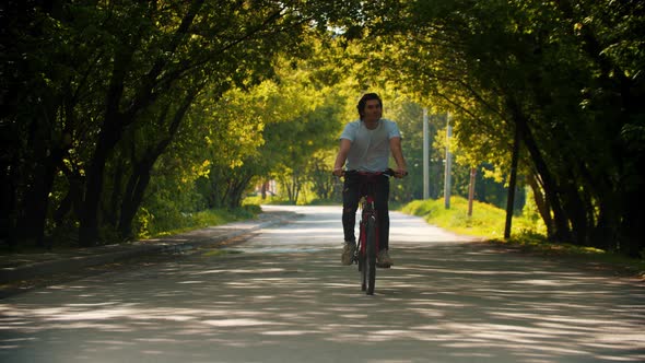 Young Smiling Happy Man in White Shirt Riding a Bike