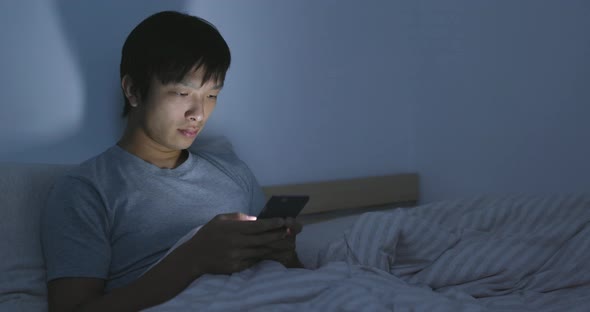 Asian man using cellphone and feeling eye dried 