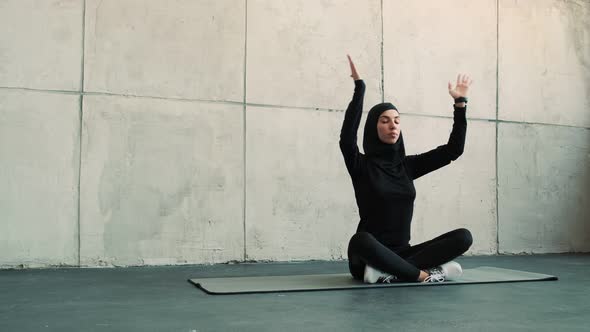 An arabian sports woman wearing a national hijab is doing yoga exercises