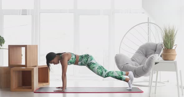 Black woman in sportswear doing workout burning fat calories at home.