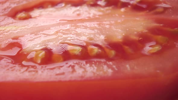 Dolly macro shot of wet cut Roma tomato with seeds. 