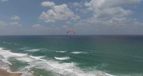 Powered Paraglide flying above a sunny beach.