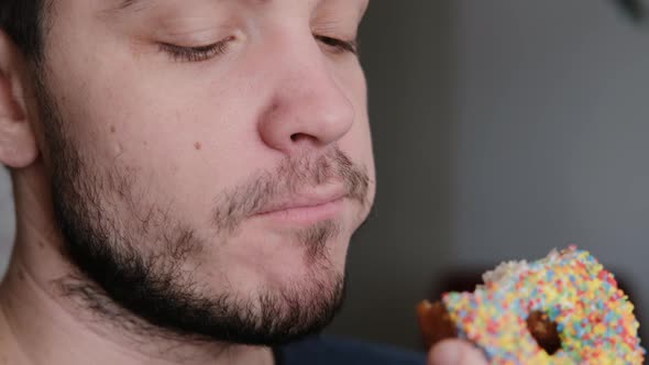 Young Guy Bites a Delicious Donut and Enjoys Its Sweet Taste