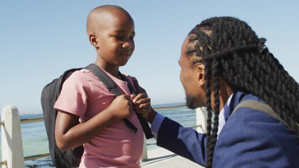 Video of happy african american father and son talking by sea