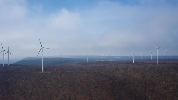 Aerial drone hyperlapse of mountain wind turbines spinning in the wind and clouds