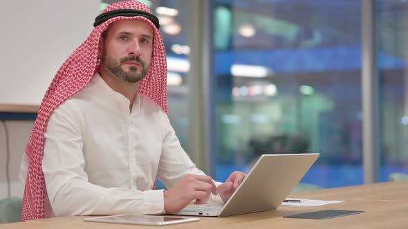 Arab Businessman with Laptop Looking at Camera