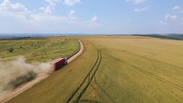 Aerial View of Cargo Truck Driving on Dirt Road Between Agricultural Wheat Fields Making Lot of Dust