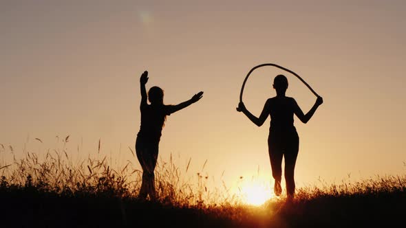 Training in the Fresh Air - a Silhouette of a Woman Jumping Over a Rope at Sunset