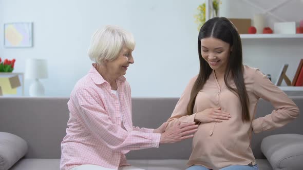 Happy Senior Woman Holding Pregnant Granddaughters Tummy, Family Replenishment