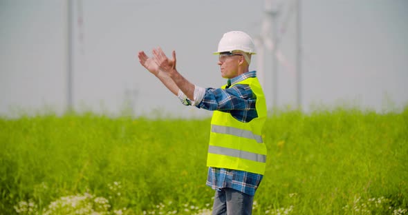 Engineer Directing By Windmills in Farm Against Sky