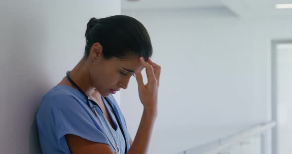 Sad female surgeon standing in corridor