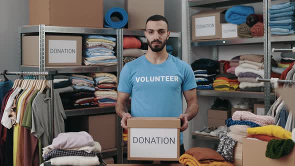 Portrait View of the Caucasian Volunteer Man Holding Cupboard Box with Donation Word and Looking at