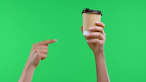 A Woman's Hand Holds a Paper Cup with Coffee the Other Hand Points with a Forefinger to Coffee and