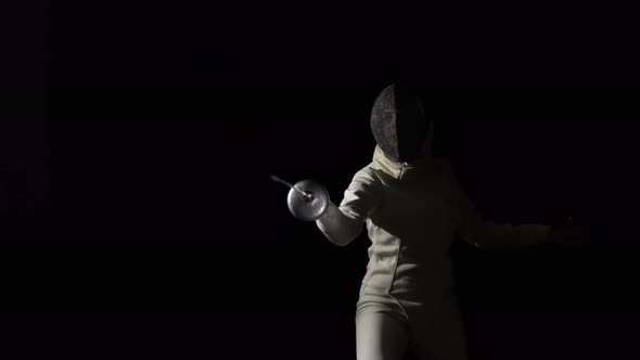 Portrait of Young Woman Fencer in Protective Helmet Becomes Fighting Position and Makes an Attacking