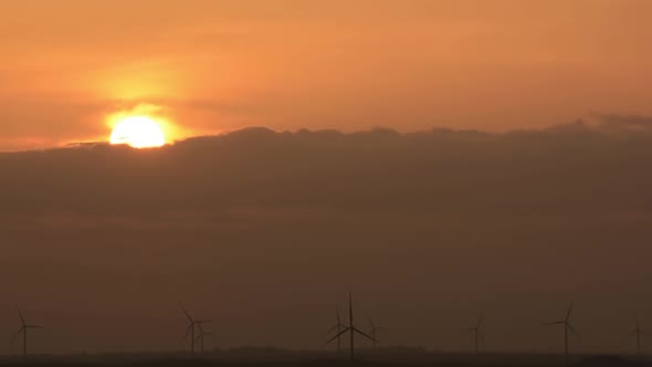 Beautiful sunset with the colorful cloudy sky with spinning wind turbines for electrical power gener