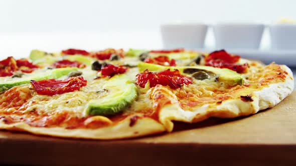 Baked pizza with avocado, cherry tomato and olive toppings